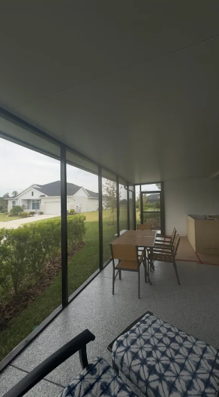 Screened room interior with dining table and floor-to-ceiling windows