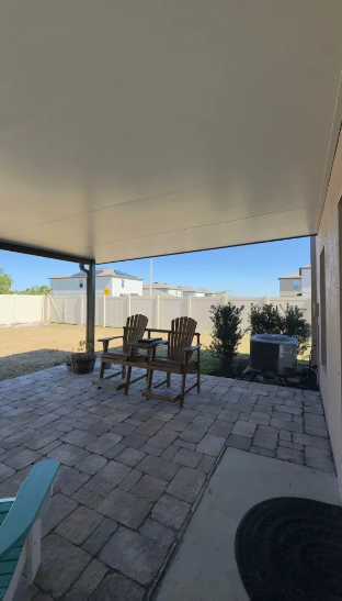 Covered patio with Adirondack chairs on paver surface