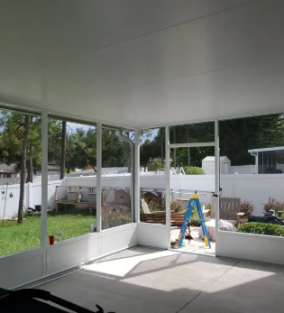 White aluminum sunroom with large windows and backyard views