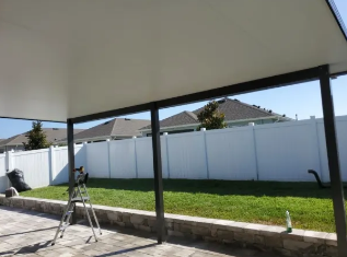 Aluminum patio cover with black frame and white privacy fence