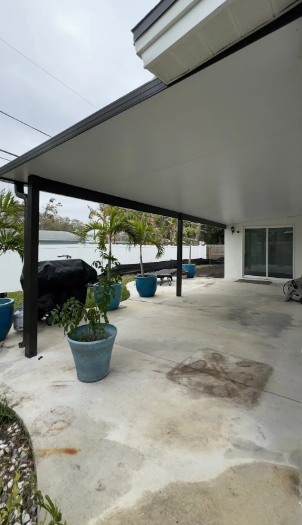 Waterfront covered patio with black aluminum structure and tropical plants